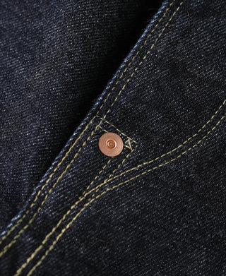 Indigo denim jeans side seam close-up with copper rivet and yellow stitching