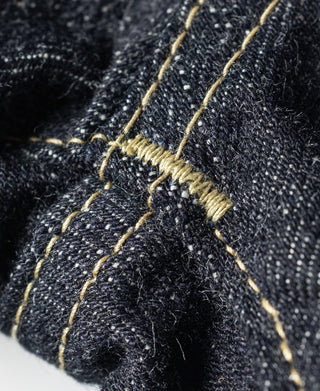 Indigo denim seam close-up with gold contrast thread and reinforced stitching