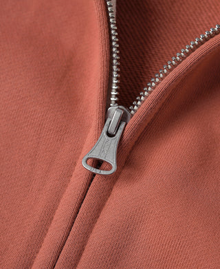Brick red terry cloth hoodie zipper close-up with metal ring pull