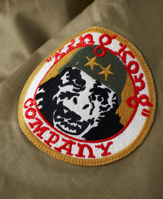 Olive jacket sleeve patch with eagle-and-stars graphic and red border embroidery.