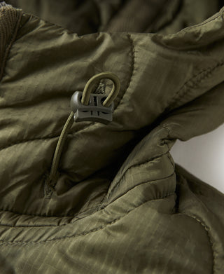 Olive quilted jacket with front zipper, ring pull, and insulated fabric panels
