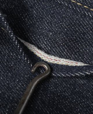 Indigo denim seam detail with metal rivet and light contrast fabric at join