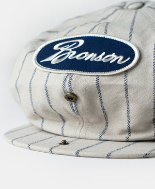 Gray railroad stripe newsboy cap with Bronson oval patch and front buttons