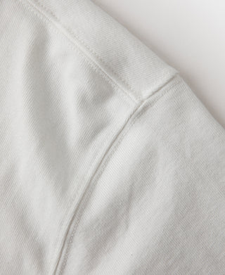 White tubular athletic t-shirt side seam detail with neat stitching, close-up.