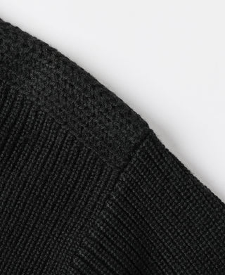 Black knit sweater sleeve shoulder close-up with ribbed texture