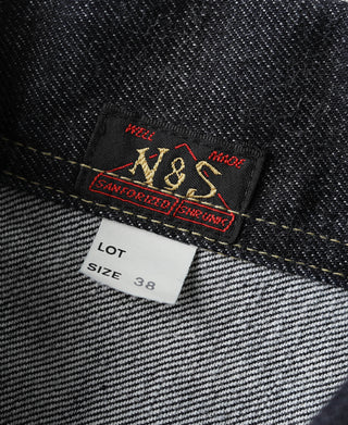 Denim jacket label near hem: N&S Universal size 38 tag on indigo fabric