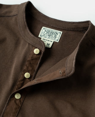 Coffee-brown henley shirt close-up with logo patch and three light buttons