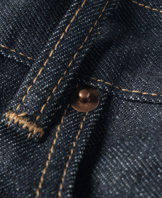 Indigo denim jeans fly area with copper button and tan bar-tack stitching