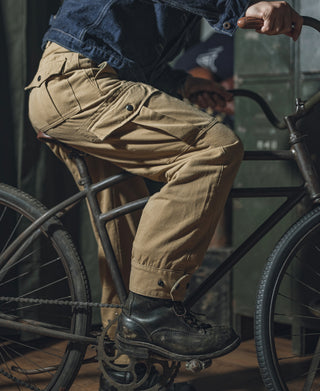 Khaki field pants on a model, relaxed leg with cargo pockets and cuff buttons.