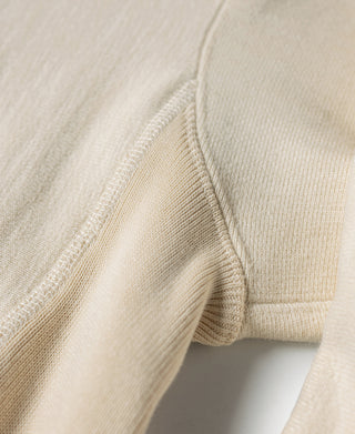 Apricot reverse-weave hoodie side seam and ribbed cuff hem detail.