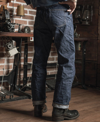 Dark indigo selvedge denim jeans on boots, showing front seams and relaxed leg fit
