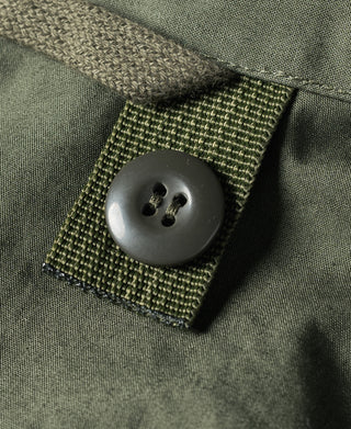 Olive green parka fabric with woven patch and large dark button