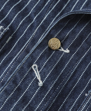 Indigo pinstripe coat placket detail with brass-tone round button and hook closure