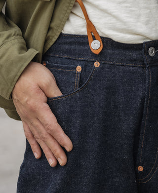 Indigo denim jeans close-up with leather-brown pocket rivets and stitch details