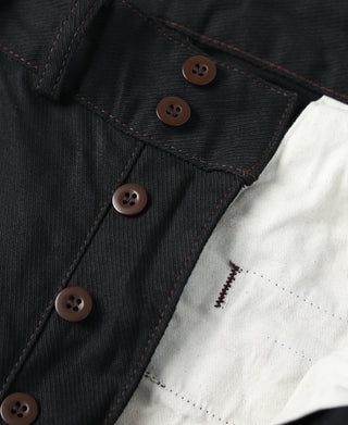 Close-up of black breeches front with multiple brown buttons and inner placket.