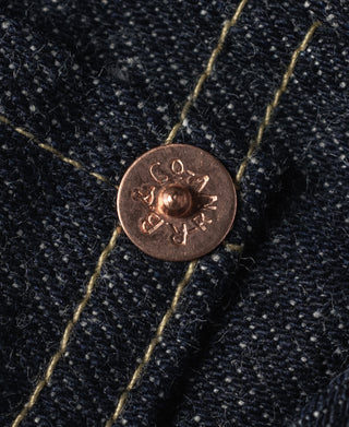Indigo denim pocket rivet with embossed copper-tone button and contrast stitching