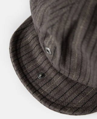 Close-up of dark gray striped newsboy cap brim with metal snap button