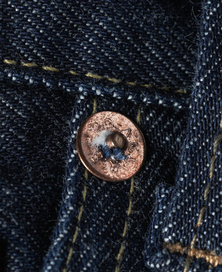 Copper-tone front button on indigo denim with worn, textured fabric