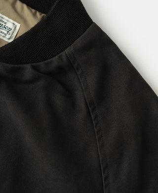 Black bomber jacket sleeve with subtle seam lines and smooth moleskin texture