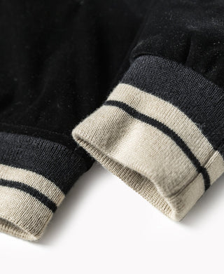 Reversible jacket cuff in cream rib knit with dark stripes on black fabric.