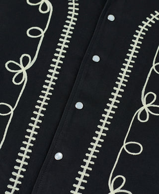 Black jacket embroidered front close-up with light thread scrollwork and round buttons