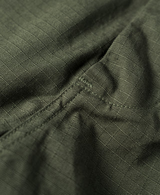 Olive fatigue pants fabric close-up with textured weave and seam stitching