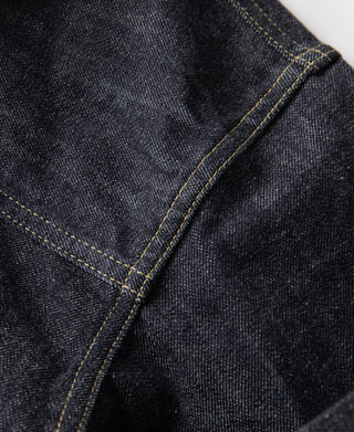 Indigo denim sleeve seam close-up with contrast stitching and metal cuff button