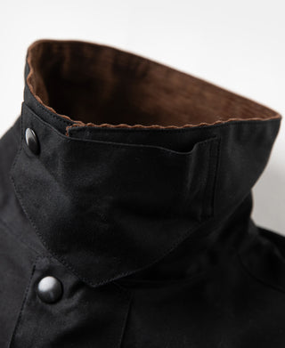 Black waxed chore jacket with buttoned collar and brass snap detail