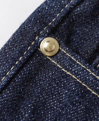 Indigo denim jeans with round metal button and contrasting yellow stitching, close-up