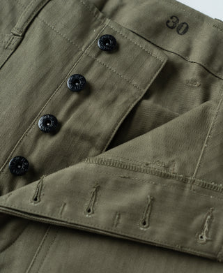 Olive trousers waist detail with dark snap buttons and stitched panel