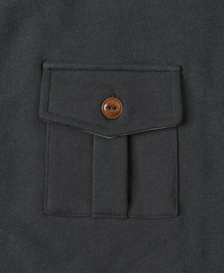 Black flap chest pocket with brown button on military-style sweatshirt.