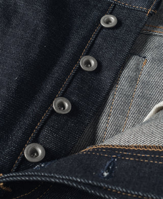 Indigo denim jeans with metal snap buttons and tan seam stitching detail