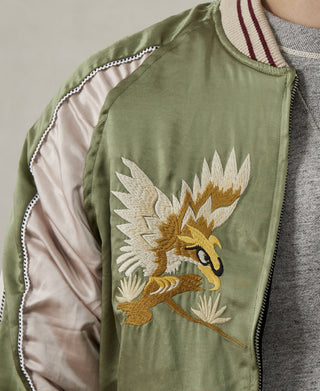 Close-up of green jacket front with winged bird embroidery and white contrast trim