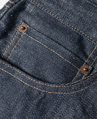 Dark blue denim jeans with curved back pocket yoke and copper rivets