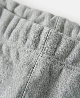 Gray terry cloth sweatpants with elastic waistband, side seam close-up.