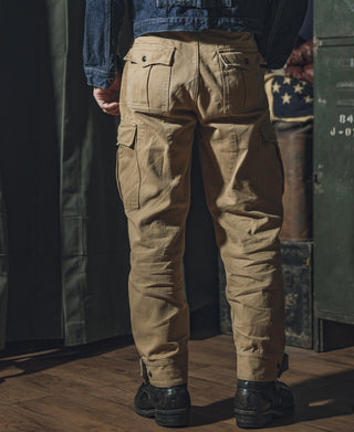 Khaki field pants on model, back view with flap pockets and relaxed cuffs.