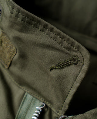 Olive parka pocket flap with reinforced stitching and metal snap hardware