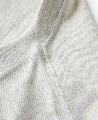 Oatmeal T-shirt shoulder and sleeve seam close-up, smooth knit texture.