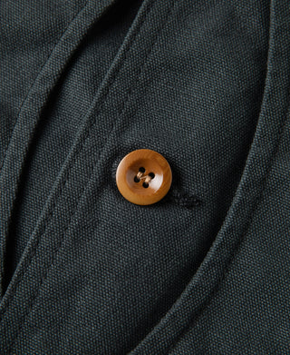 Dark green canvas vest fabric texture with round brown button on placket