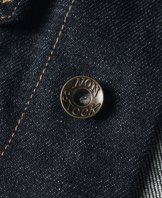 Indigo denim jacket button with embossed “NON STOCK” detail