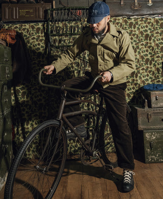 Olive green field jacket on man, stand collar with button front and cuffs