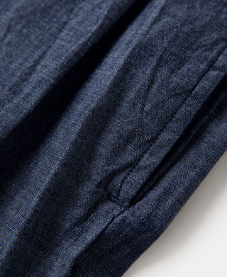 Indigo chambray pants fabric close-up with pleats and inner seam stitching