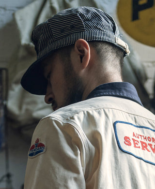 Railroad engineer cap viewed from back on model, striped crown and dark brim