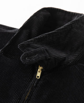 Black corduroy jacket shoulder detail with gold zipper pull and ribbed texture