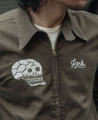 Olive jacket close-up of front white skull patch and “Jack” script embroidery