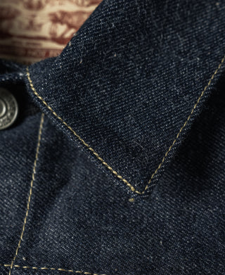 Indigo denim jacket neckline with triangular seam and yellow contrast stitching.