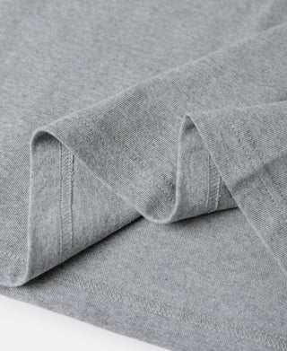 Gray cotton tubular T-shirt knit fabric close-up with seam and folded sleeve edge.