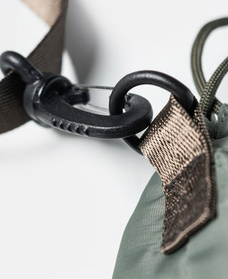 Chalk bag hardware: black ring and clip attached to olive webbing strap