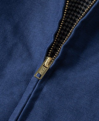 Gold-tone zipper pull on blue jacket front with houndstooth-lined edge