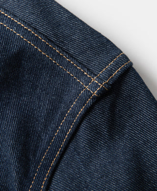 Indigo denim jacket seam close-up with double-needle stitching and cross seam.